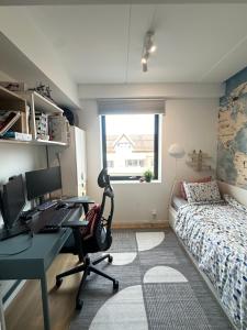 Schlafzimmer mit einem Schreibtisch, einem Computer und einem Bett in der Unterkunft Stylish apartment in a fun neighborhood in Lillestrøm