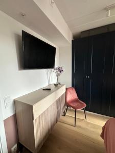 une chambre avec une commode avec une chaise rouge et une télévision dans l'établissement Stylish apartment in a fun neighborhood, à Lillestrøm