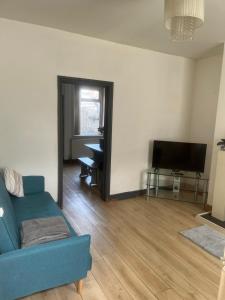 ein Wohnzimmer mit einem blauen Sofa und einem TV in der Unterkunft Cosy Widnes Home in Widnes