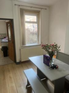 Cosy Widnes Home في ويدنز: غرفة مع طاولة مع إناء من الزهور عليها