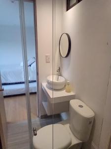 een badkamer met een toilet, een wastafel en een spiegel bij HOMY APARTAMENTOS - Corferias, embassy, airport, G12, UN, Agora in Bogota