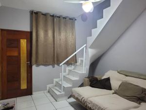 Una sala de estar con una escalera y un sofá. en Sobrado de condominio Praia Grande VilaTupi com 2 dormitorio, en Praia Grande