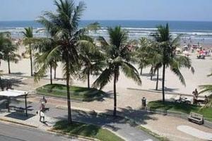 una playa con palmeras y gente caminando por la playa en Sobrado de condominio Praia Grande VilaTupi com 2 dormitorio, en Praia Grande