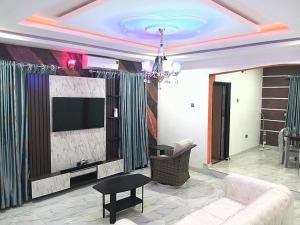 ein Wohnzimmer mit einem Sofa und einem TV in der Unterkunft Feyintola Shortlet Apartment in Ondo
