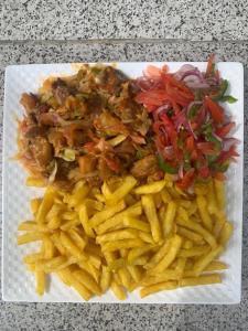 a plate of food with french fries on a table at JOSELLA MOTEL MUBENDE in Mubende