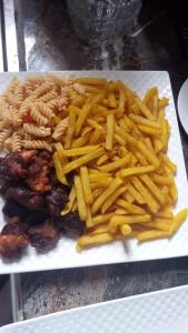 un plato de pasta y papas fritas en una mesa en JOSELLA MOTEL MUBENDE, en Mubende