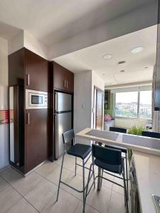 a kitchen with a counter and chairs and a refrigerator at Topikos Apartments in Ayia Napa