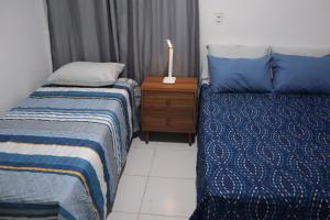 1 dormitorio con 2 camas y mesita de noche con lámpara en Studio Casa Amarela - a 400m do Corredor Cultural, en Mossoró