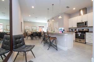 a kitchen and living room with chairs and a counter at Magical Themed House Just 5 Minutes to Disney Free BBQ Pool Access in Orlando