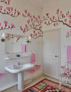 a bathroom with a sink and pink flowers on the wall at Domaine Maze Churchill in Burie