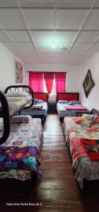 a row of beds in a room with pink curtains at Hotel Arte Santa Rosa in Santa Rosa de Cabal