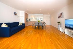 a living room with a blue couch and a wooden floor at Two-Bedroom Flat Chiswick in Kew Bridge