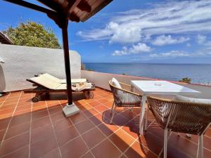 um pátio com uma mesa e cadeiras e o oceano em Villa Delfines em Agulo