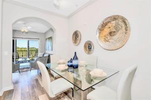 a dining room with a glass table and white chairs at 3BR Condo - Games Hot Tub Sauna - Near Disney in Orlando
