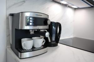 a coffee maker on a counter with two coffee cups at Alice Apartament in Gliwice