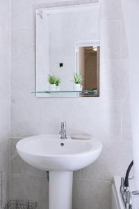 a white bathroom with a sink and a mirror at Hampton Court Cottage in Hampton +32 photos