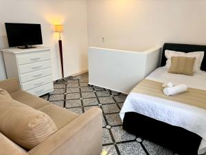 um quarto com uma cama, um sofá e uma televisão em 15 min Aeroporto Internacional de Guarulhos, 10 min centro GRU em Guarulhos