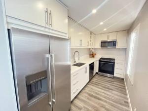 a kitchen with white cabinets and a stainless steel refrigerator at 1BD Modern Venice Beach 12A in Los Angeles