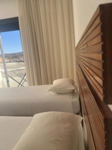 two beds in a hotel room with a window at Prada appartement Essaouira in Essaouira