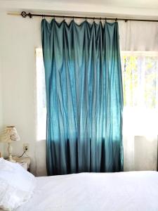 Una cama con una cortina azul junto a una ventana en 海之恋 en Arazato