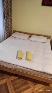 a bed with white sheets and two yellow pillows at Apartment On Katedralna in Lviv
