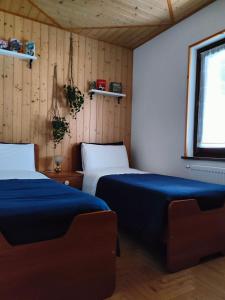 2 Betten in einem Zimmer mit Holzwänden in der Unterkunft Haisle im Untrborkh in Sauris
