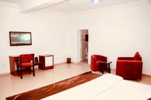 1 dormitorio con sillas rojas, 1 cama y 1 mesa en Executive Gold Hotel, en Abuja