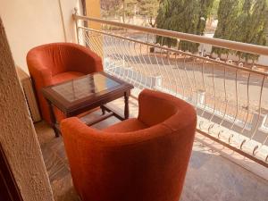 2 sillas naranjas y una mesa en el balcón en Executive Gold Hotel, en Abuja