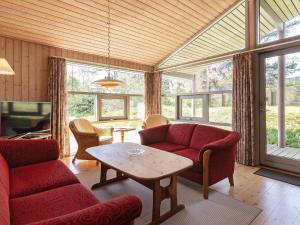 una sala de estar con sofás rojos y una mesa. en Splendid Holiday Home in Hadsund with Sauna, en Øster Hurup