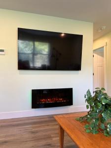 a living room with a fireplace with a tv on the wall at Wellington House in Nanaimo