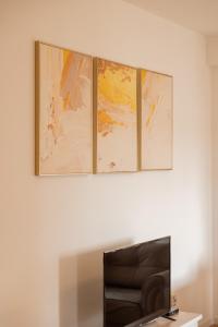 three paintings on a wall above a black chair at Apartment 5 in Pristina