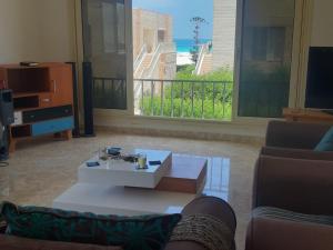 ein Wohnzimmer mit einem Couchtisch und Meerblick in der Unterkunft شاليه الساحل الشمالي in Dawwār Shindī Fannūsh
