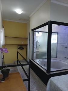 een badkamer met een bad met een glazen wand bij Miragem Chalés in Serra Negra