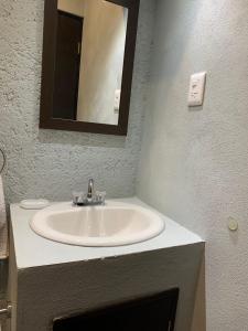 a bathroom with a white sink and a mirror at Residencial Edzna in Campeche