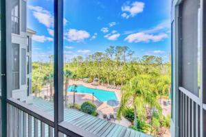 a balcony with a view of a pool and palm trees at Bright 2BR Condo with Pool and Hot tub - near Disney! in Orlando