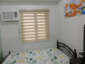 a bedroom with a bed and a window with a microwave at MJC's Stay and Relax in Marilao