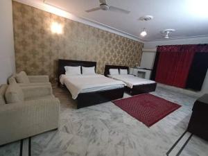 a hotel room with two beds and a couch at RoyalVilla Guest House Karachi in Karachi