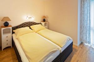 een bed met gele lakens en kussens in een slaapkamer bij Fewo-Mientje-2-Haustiere-erlaubt-WLAN-kostenlos in Norddeich
