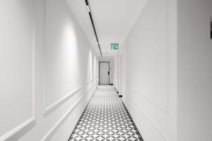 an empty corridor with white walls and black and white flooring at Collect Residence in Budapest +53 photos