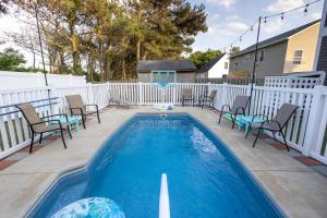 a swimming pool with chairs and a white fence at Voyage Anchor in Nags Head