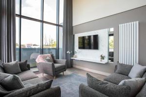 uma sala de estar com sofás e uma televisão e janelas em Skyline Serenity: Exquisite 3-Bedroom Ultra-Luxury Penthouse em Belfast