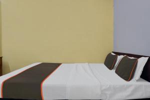 1 dormitorio con 1 cama blanca y 2 almohadas en Collection O HOTEL DAULAT INN, en Lonavala
