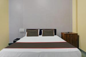 1 dormitorio con 1 cama blanca grande y mesita de noche de madera en Collection O HOTEL DAULAT INN, en Lonavala