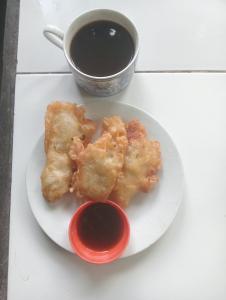 a plate with two pieces of food and a cup of sauce at ATB Hostel in Lovina