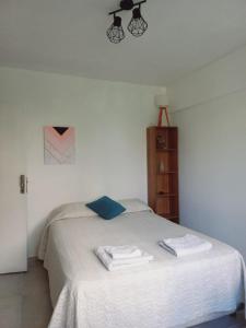 um quarto com uma cama branca e toalhas em Hermoso monoambiente en ciudad de Mendoza. em Mendoza
