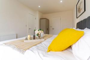 Una cama blanca con una almohada amarilla y flores. en Bridge Court by Sterling Edge Apartments - Luxury Aparthotel - Stylish 1-bed Apartments - Balcony with Canal View or Private Garden - Free Parking en Birmingham