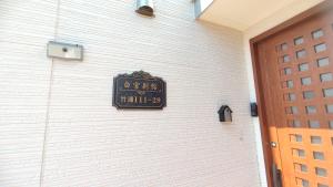 a clock on the side of a white wall at White House Onsen Guesthouse in Shiraoi