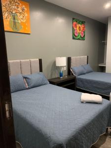 a bedroom with two beds and a table with a lamp at Residencial Edzna in Campeche