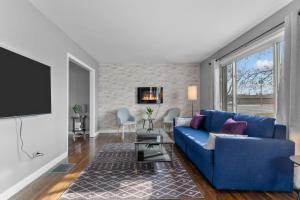 a living room with a blue couch and a tv at Cheerful Family Home - 3 mins drive to UWindsor in Windsor