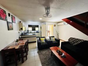 a living room with a table and a kitchen at Cozy, Comfortable, Family Home. in Nadi